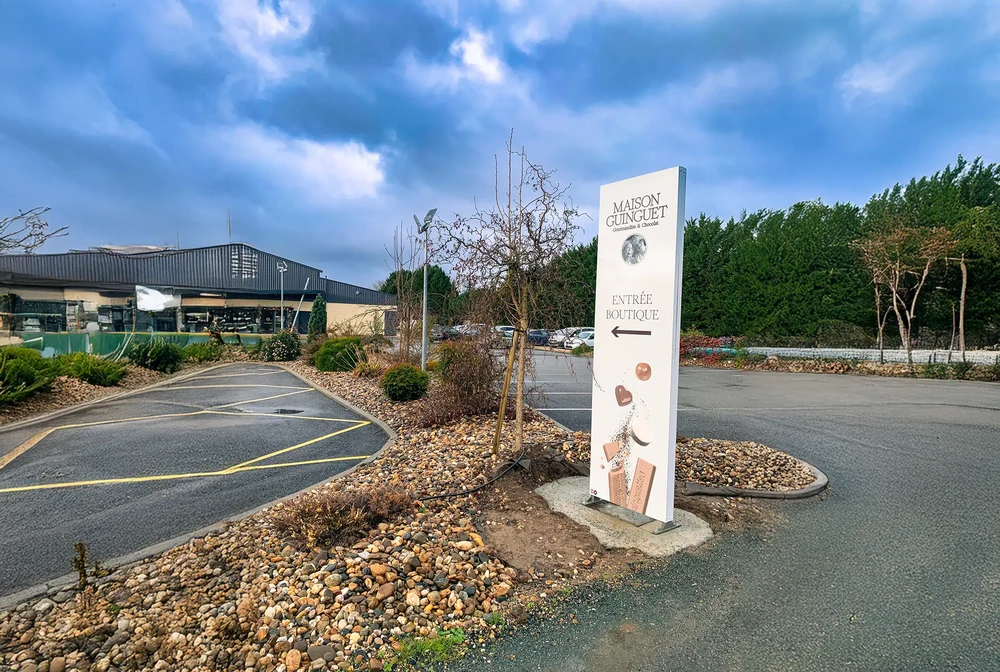 Enseigne lumineuse de magasin "FairePlay!" avec slogan "Le concept store engagé et responsable" sur mur bleu éclairé par spots