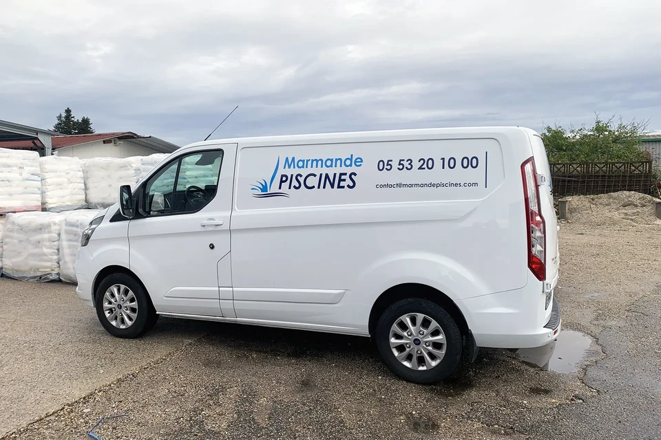 Un homme souriant dans un véhicule utilitaire gris fait un signe de pouce levé par la fenêtre ouverte côté conducteur