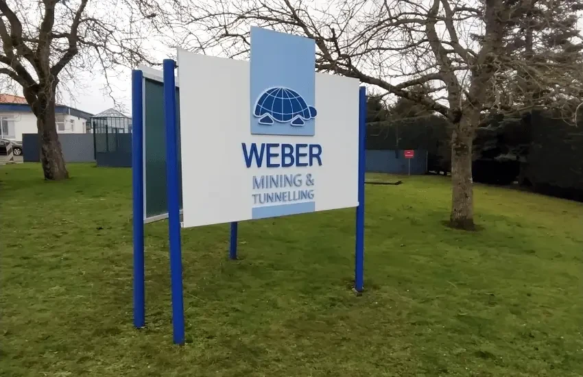 Scène extérieure avec panneau publicitaire noir fixé sur clôture en bois vieilli