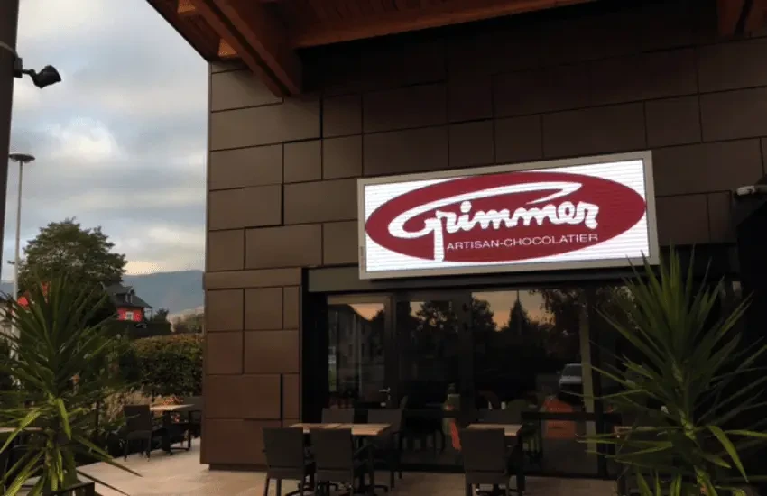 Enseigne lumineuse de magasin "FairePlay!" avec slogan "Le concept store engagé et responsable" sur mur bleu éclairé par spots